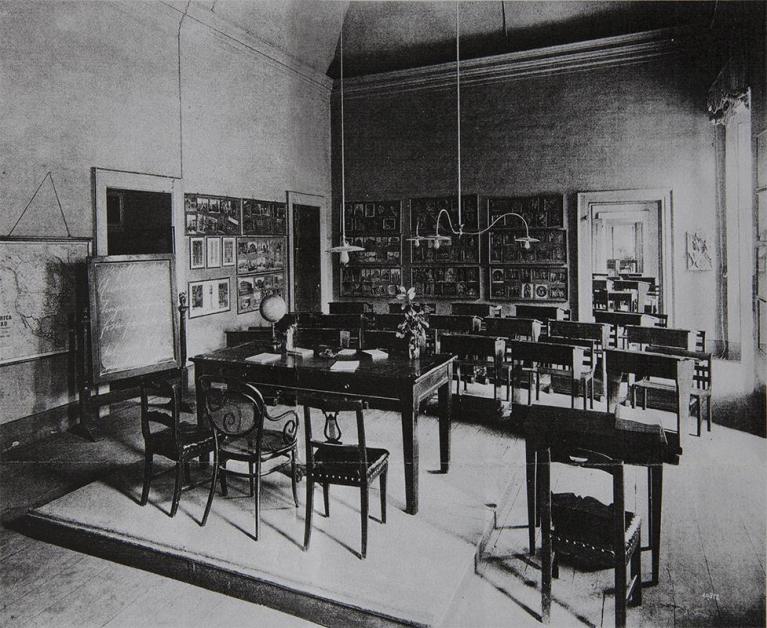 Aula scolastica nel palazzo Archinto in Milano. La fotografia del 1908 dimostra che l’uso di accostare su pannelli riproduzioni di opere d’arte appartenenti ad epoche diverse era in uso nella didattica dell’arte. Warburg lo adotta per mettere a punto il suo metodo storico-artistico. Mnemosyne, l’atlante figurativo composto da una serie di tavole che Warburg presenta per la prima volta alla Biblioteca Hertziana di Roma il 19 gennaio 1929, nasce da una pratica in uso nella didattica dell’arte che consente allo studioso di “vedere” il rapporto anacronistico dell’opera d’arte visiva con la storia. Warburg lo “vede” non solo attraverso l’utilizzo della fotografia e delle tecniche del collage e del montaggio cinematografico, come sostenuto da alcuni studiosi.