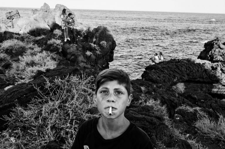 ©DanieleVita_World Report Award_FFE21. Agatino, un ragazzo di 11 anni del quartiere di San Cristoforo, tiene in bocca una sigaretta spenta. La sua estate è stata segnata dai primi amori, le prime sigarette, i primi spinelli e molti tuffi. Agatino è uno dei pochi che si tuffa dal campo di basket, a un'altezza di 30 metri.