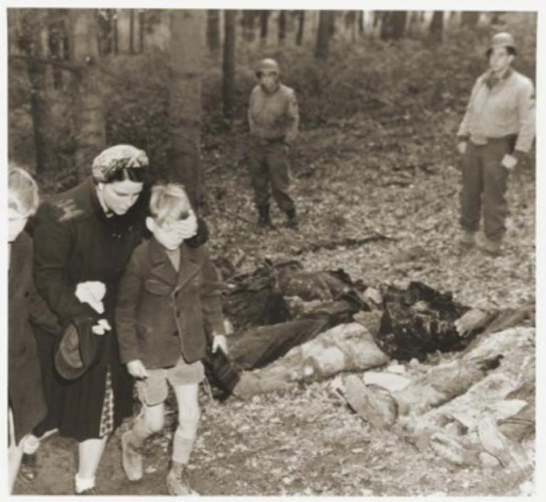Una madre nel Sauerland passa con il figlio vicino a una fossa comune con i corpi di 57 operaie e operai coatti russi uccisi, scoperta il 3 maggio 1945 vicino a Suttrop. (United States Holocaust Memorial Museum, courtesy of National Archives and Records Administration, College Park).